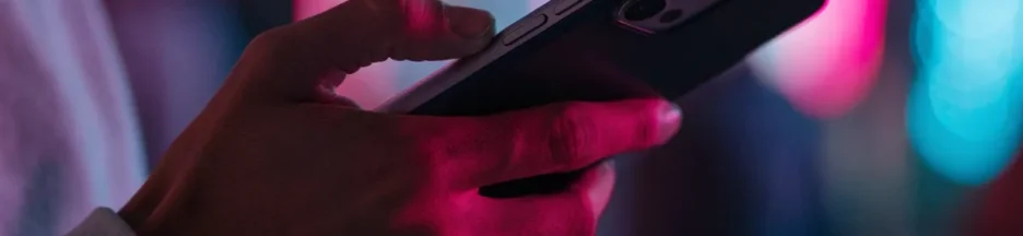 une main tient un smartphone qui filme une scène éclairée par des néons colorés évoquant Rosé de BLACKPINK