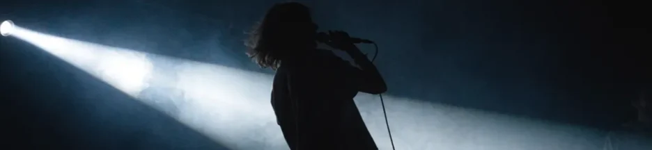 un chanteur évoquant Eddy de Pretto seul sur une scène sombre