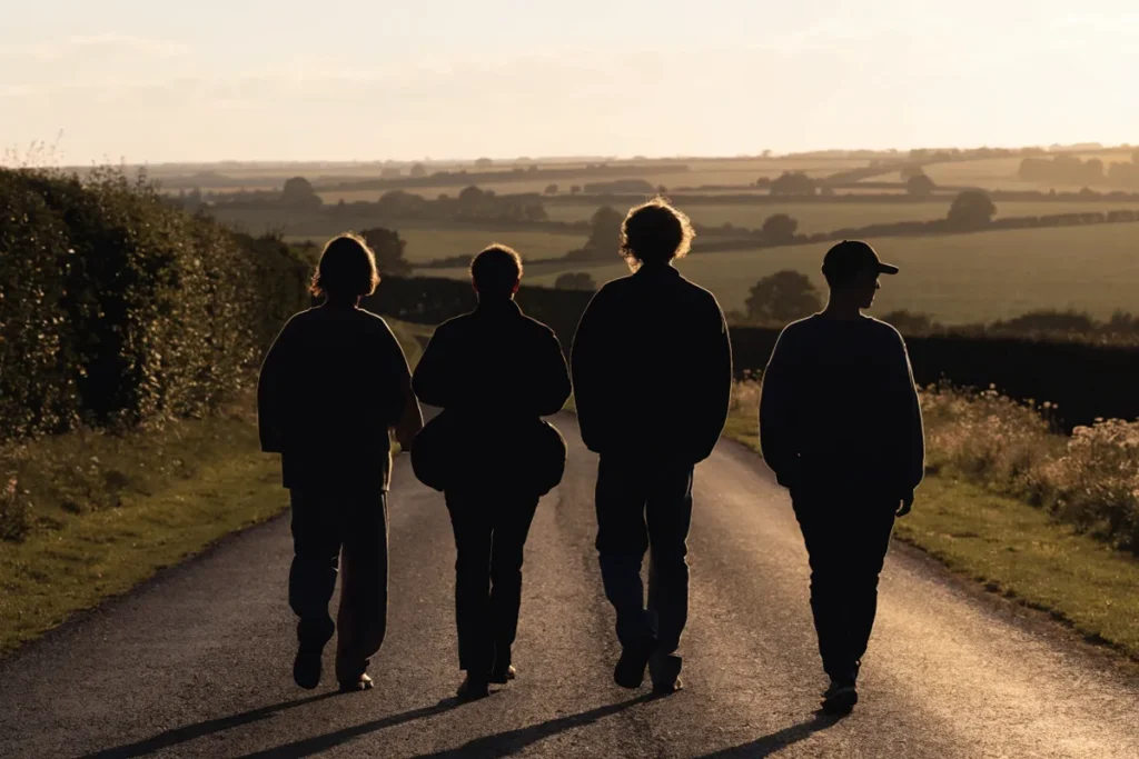 silhouettes de quatre amis de dos sur une route anglaise évoquant The Inbetweeners 3