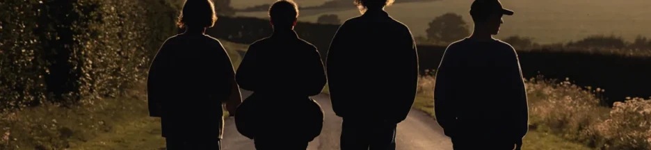 silhouettes de quatre amis de dos sur une route anglaise évoquant The Inbetweeners 3