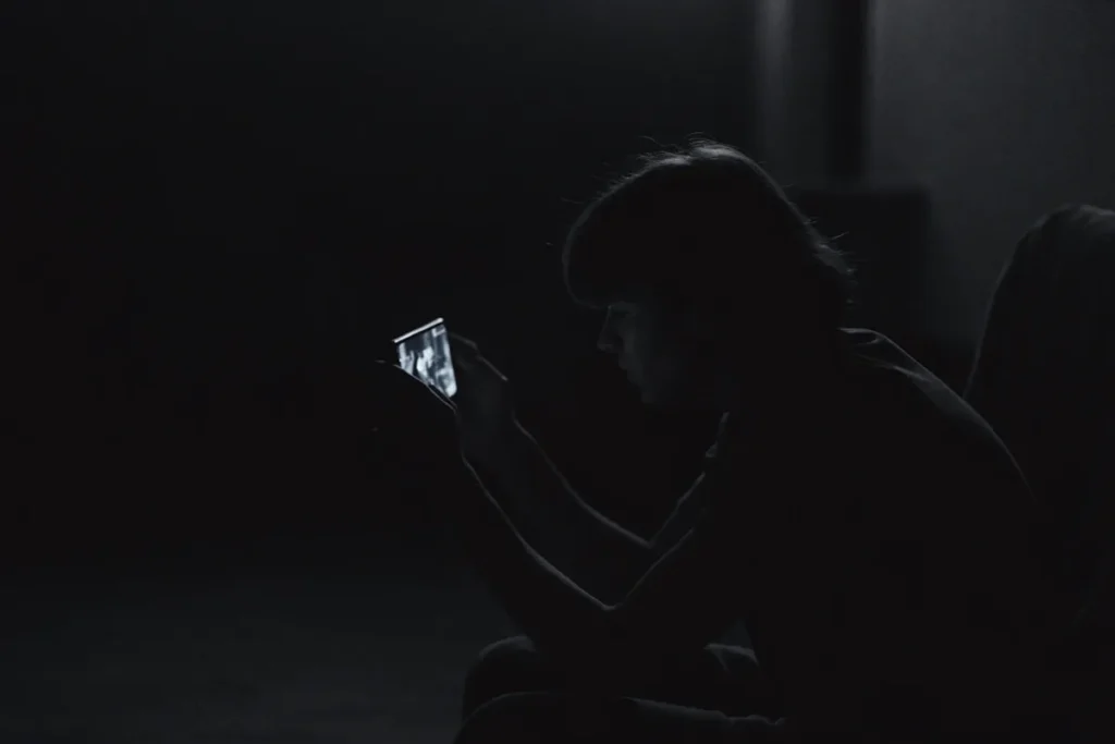Une personne de dos suit The Perfect Lie en streaming sur smartphone le soir
