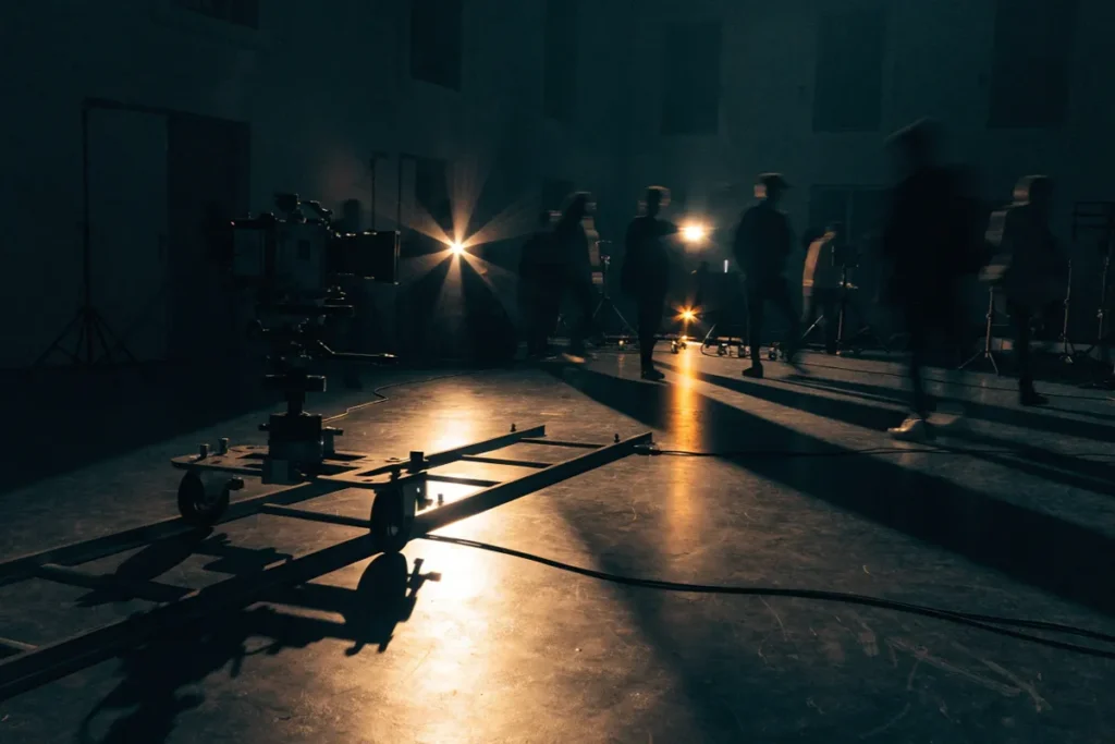 un plateau de tournage de clip musical avec caméra, rails et projecteurs allumés