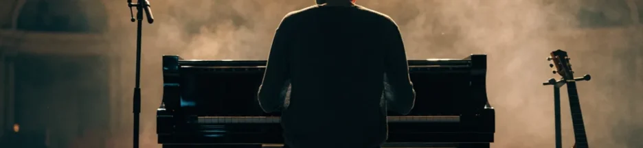 un musicien assis au piano dans un théâtre lumineux, évoquant le format intimiste du projet scénique intimiste de Calogero