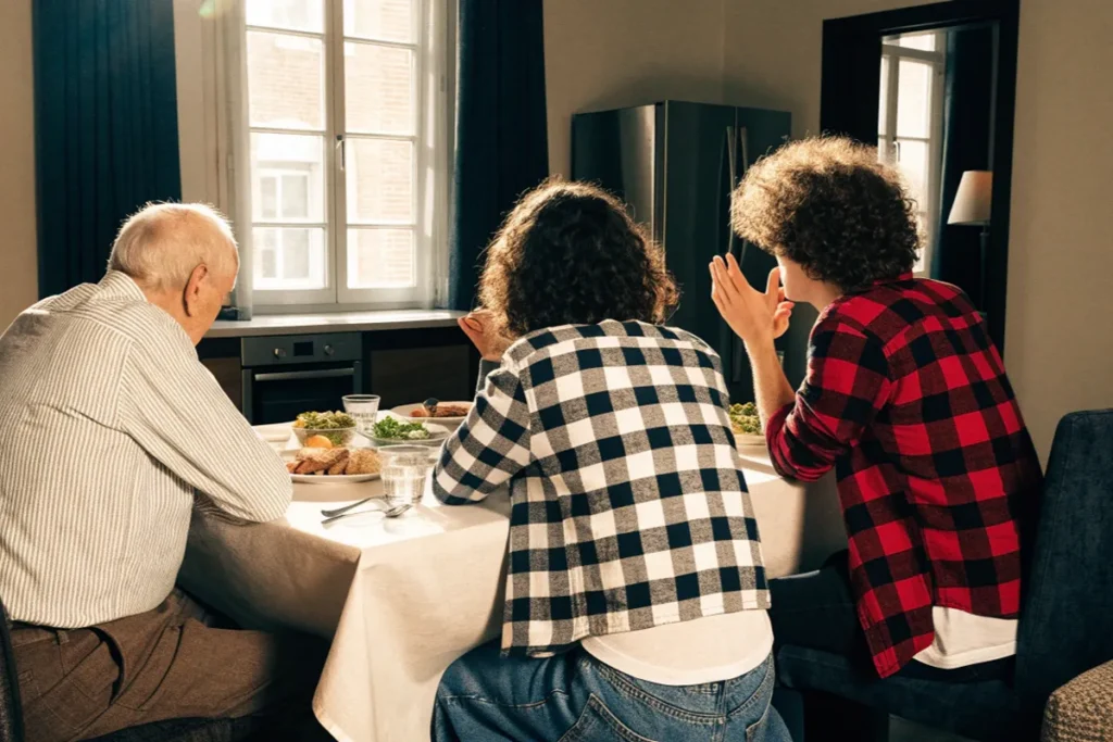 Père âgé et enfants adultes réunis autour d'une table évoquant Claude