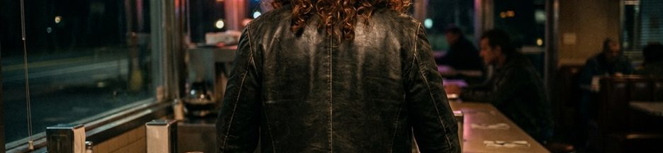 Homme aux cheveux bouclés roux-brun dans un bar