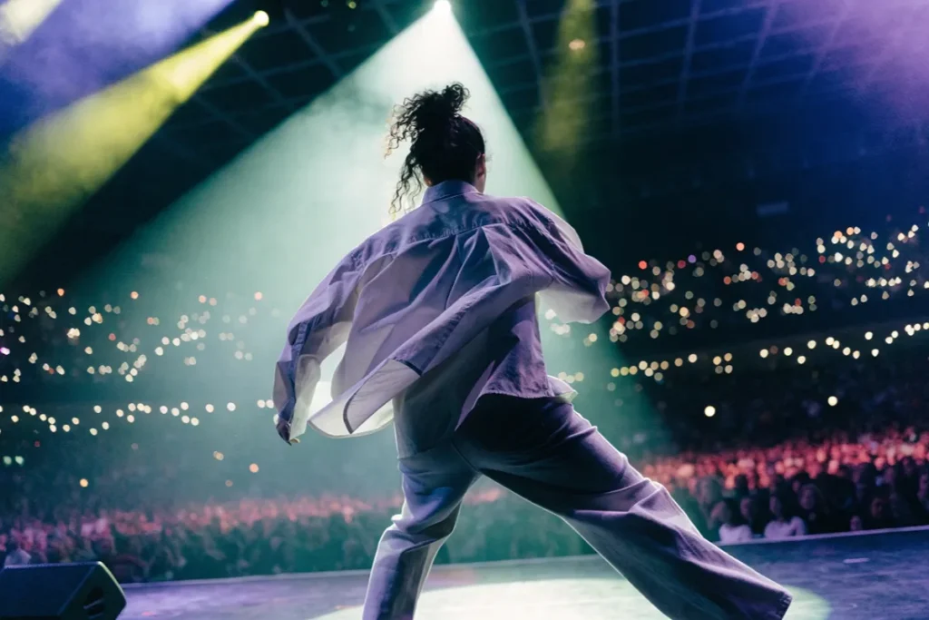 Une artiste de dos sur une grande scène de concert évoquant la future tournée de Hoshi