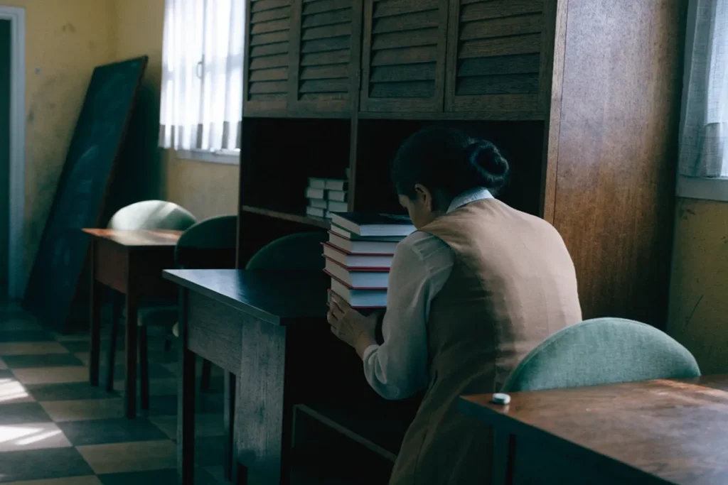 Une jeune enseignante dans une salle de classe tenant des livres évoquant le film La Tentazione