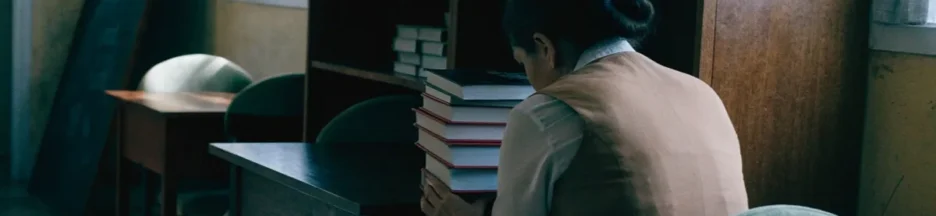 Une jeune enseignante dans une salle de classe tenant des livres évoquant le film La Tentazione