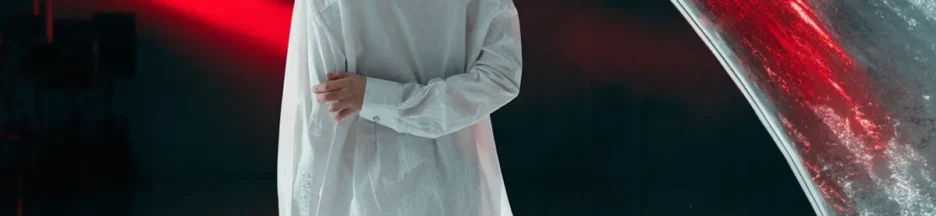 Une jeune femme dans une pièce sombre éclairée par des néons rouges évoquant PRESS PLAY de LISA