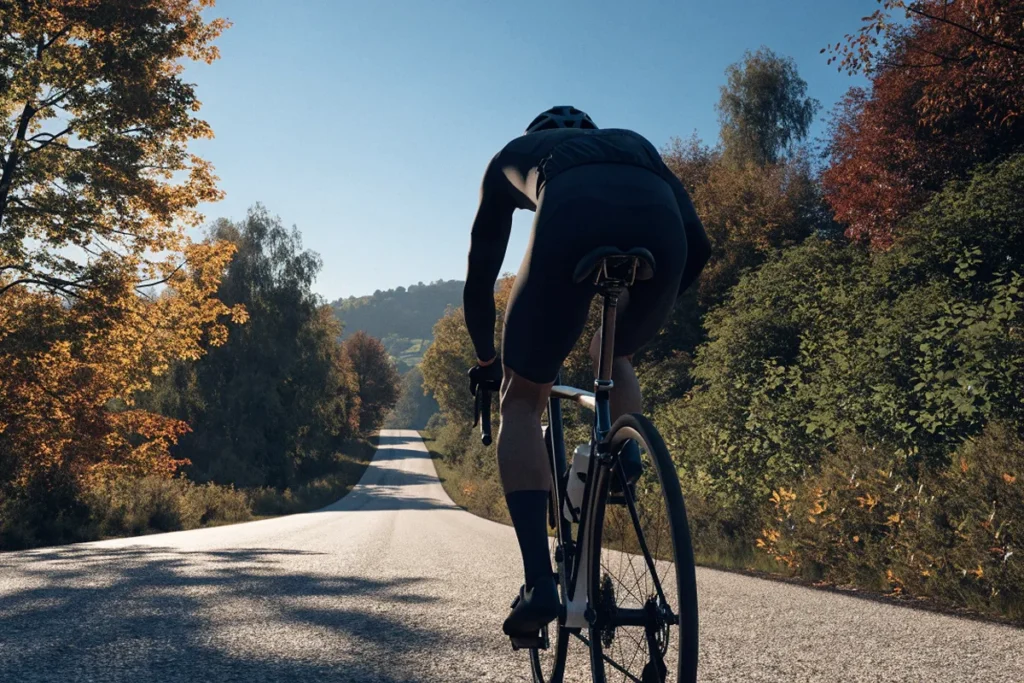 Cycliste fictif en pleine montée sous des feuillages d'automne, image évoquant Paul Seixas au Tour de Lombardie
