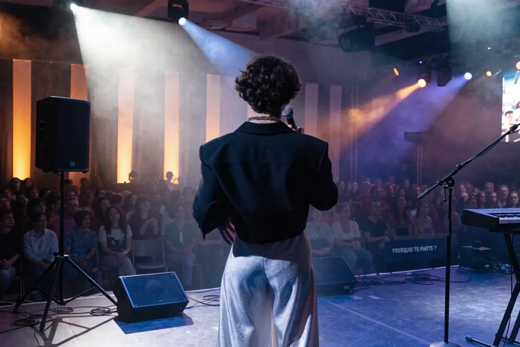 artiste face à une scène éclairée pendant un concert rappelant Pierre de Maere